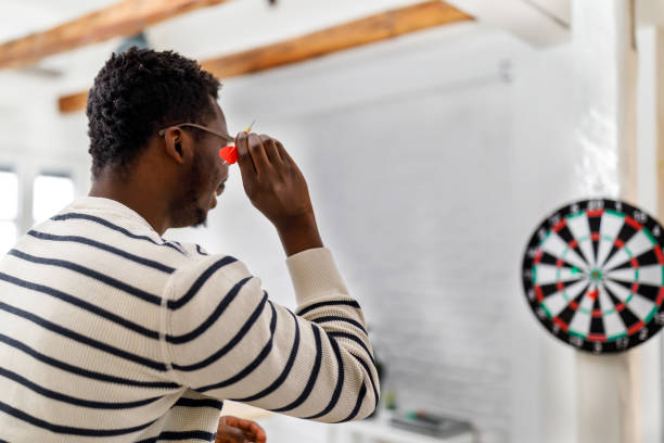 istock A young African-American man is playing darts at home. 1422144910