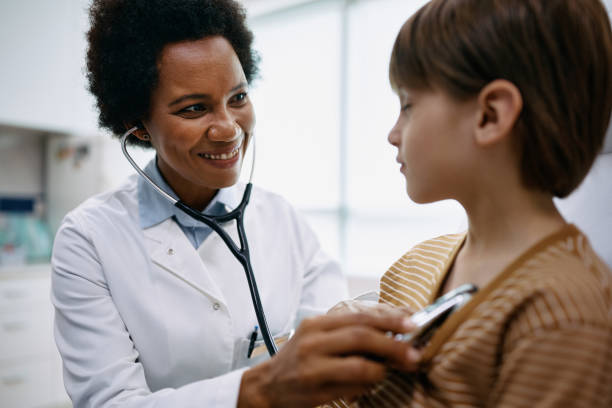 istock Happy black doctor using stethoscope while examining boy's chest at pediatrician's office. 1422146795