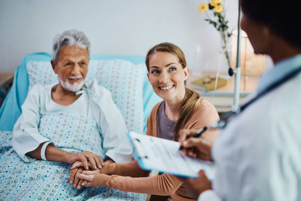 mujer feliz y su padre hospitalizado hablando con un médico en la clínica. - patient doctor hospital senior adult fotografías e imágenes de stock