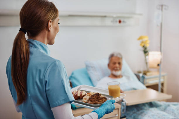 vista trasera de la enfermera que lleva el almuerzo al paciente hospitalizado. - servir comida y bebida fotografías e imágenes de stock