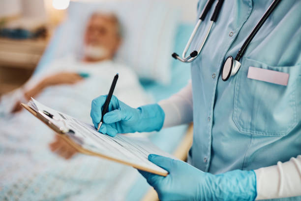 Close up of nurse writing data into medical record of hospitalized patient. stock photo