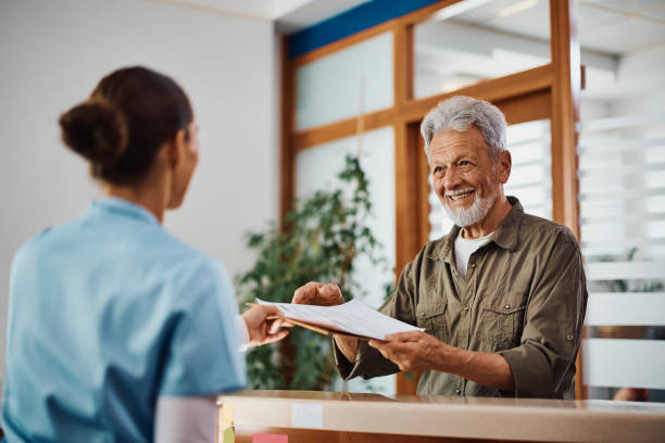 um idoso feliz pegando a papelada médica de uma enfermeira na clínica. - hospital senior adult doctor mature adult - fotografias e filmes do acervo