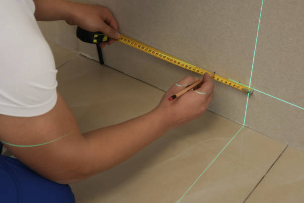 istock Worker using cross line laser level, pencil and tape for accurate measurement on plasterboard, closeup 1422150131