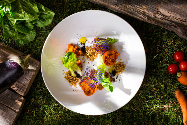 Broken muffin with raisins, lace chips, lettuce, nuts, sauce in a plate on green grass with tomatoes, zucchini, carrots and lettuce