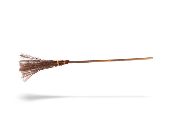 Witches broomstick or besom floating and isolated on a white background with broom shadow.