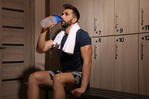 istock Handsome man drinking water in locker room 1422156321