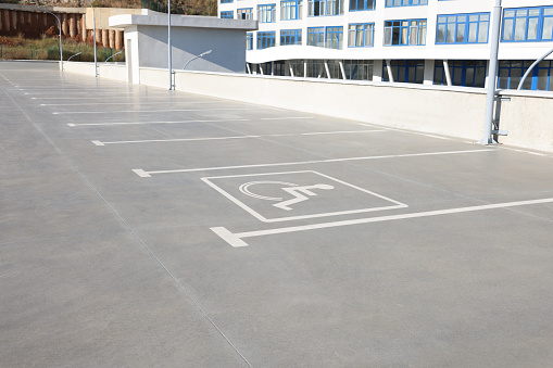 Car parking lot with white marking lines and wheelchair symbol outdoors