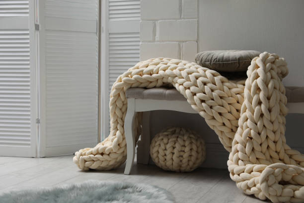 istock Indoor bench with soft chunky knit blanket, cushion and pouf in room. Interior design 1422162945