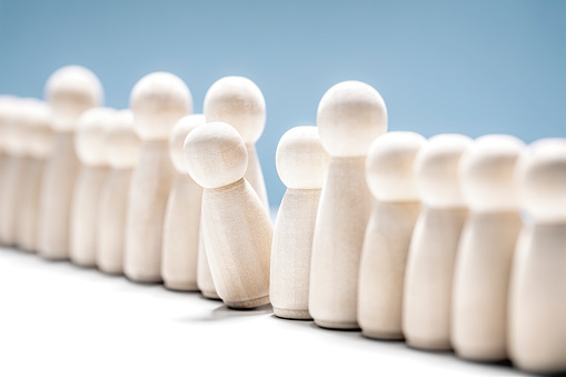 Standing out from the crowd or leadership concept wooden people in a row with one leaning forward