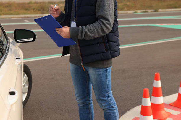 istock Instructor with clipboard near car outdoors, closeup. Driving school exam 1422165065