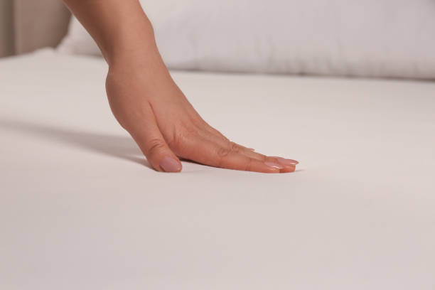 istock Woman touching soft white bedsheet, closeup view 1422165458