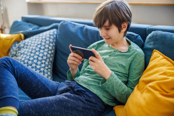 istock Preadolescent boy smiling and playing video game on smart phone at home 1422182787