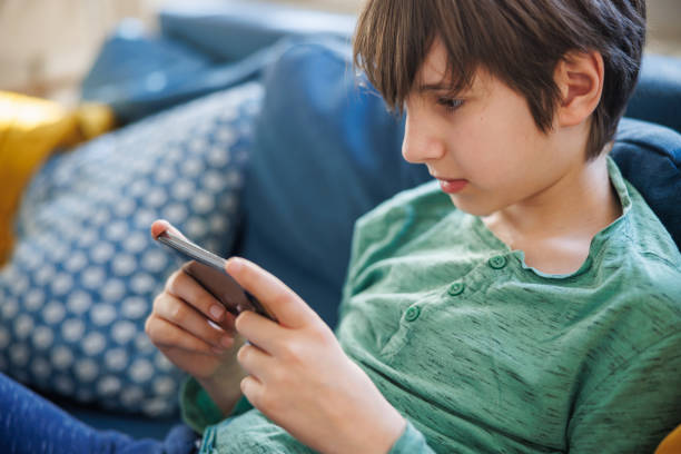 istock Preadolescent boy focused on watching content on smart phone at home 1422185052