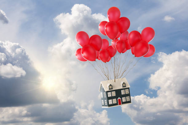Toy house with balloons floating in the sky stock photo