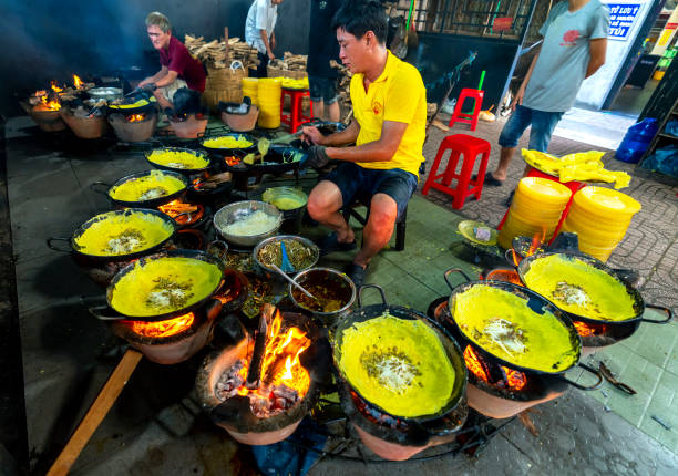 An Giang, Vietnam - September 3rd, 2022: A man Baker is making Banh Xeo on the surrounding braziers, vegetarian pancakes serving Buddhists visiting the temple in An Giang, Vietnam