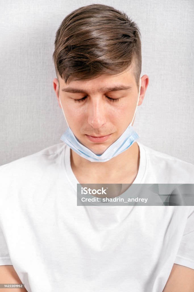 Young Man with a Flu Mask Tired Young Man in a Flu Mask by the Wall in the Room 25-29 Years Stock Photo