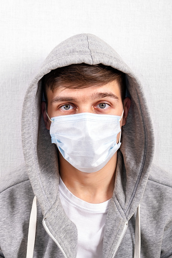 Portrait of Young Man in a Flu Mask by the Wall in the Room