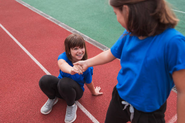Girl smiling when her friend is helping her get up during workout stock photo