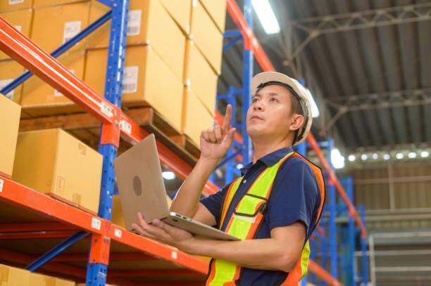 istock Young asian male worker wearing helmet using laptop in modern warehouse. 1422204215