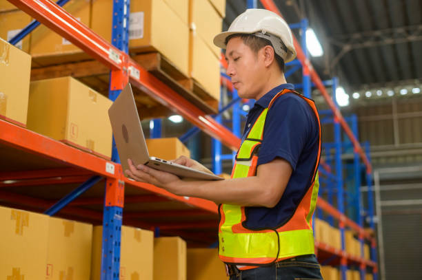istock Young asian male worker wearing helmet using laptop in modern warehouse. 1422204224