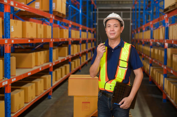 istock Young asian male worker wearing helmet using talki walki in modern warehouse. 1422207978