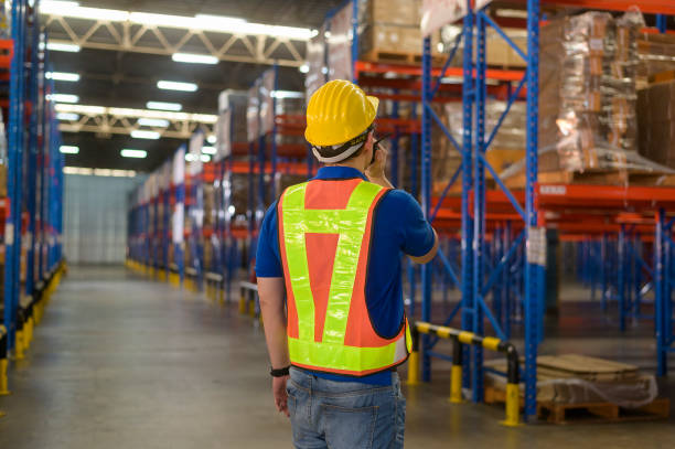 istock Young asian male worker wearing helmet using talki walki in modern warehouse. 1422208005