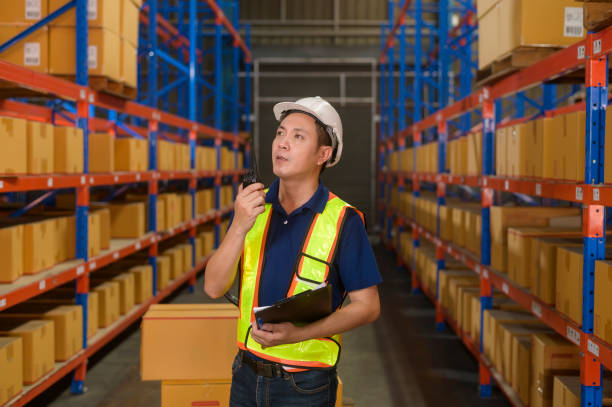 istock Young asian male worker wearing helmet using talki walki in modern warehouse. 1422208015
