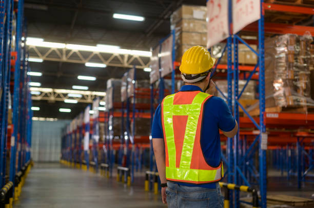 istock Young asian male worker wearing helmet using talki walki in modern warehouse. 1422208033