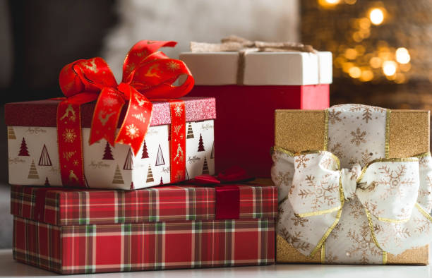 cajas de regalo y abeto sobre la mesa en el interior de la casa de la sala de estar. un concepto acogedor de vacaciones de navidad e invierno en 2022. preparación de regalos a familiares. - regalo de navidad fotografías e imágenes de stock