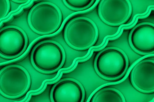 Photo of Relief surface of green silicon anti stress sensory pop it toy with with bumps and pits close up.