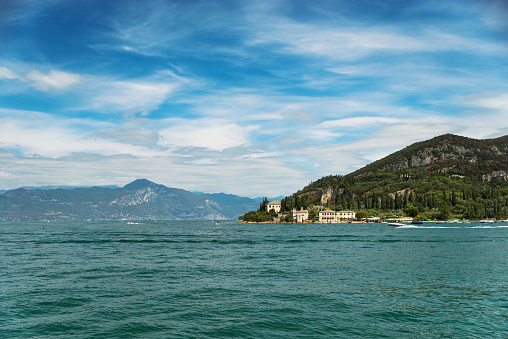 Beautiful view of Lake Garda town and cloudscape in summertime; Lake Garda is the largest lake in Italy. It is a popular holiday location in northern Italy, about halfway between Brescia and Verona, and between Venice and Milan on the edge of the Dolomites.