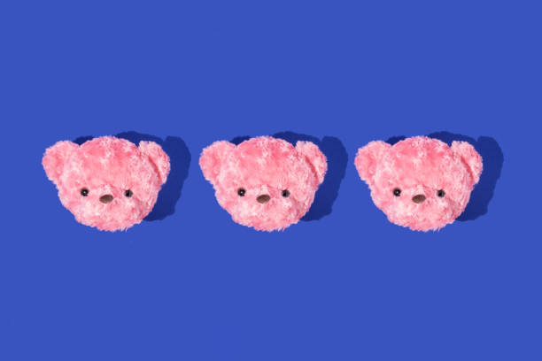 Creative pattern with pastel pink teddy bear heads on deep blue background. Aesthetic fashion concept with toy. Bold colors minimal  trendy idea.
