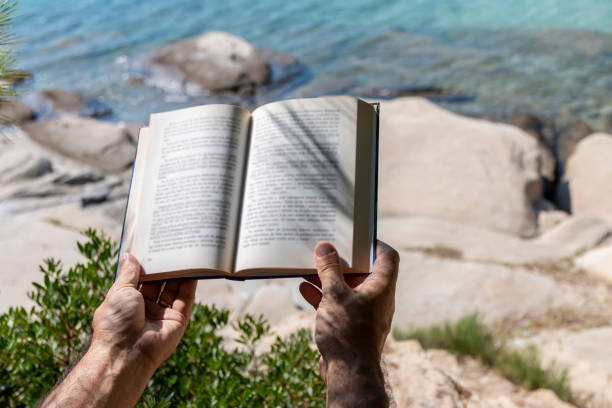istock A man is reading a book next to the see 1422221876