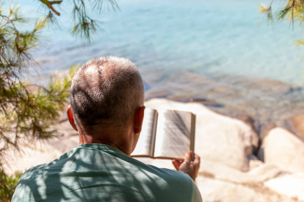 istock A man is reading a book next to the see 1422221877