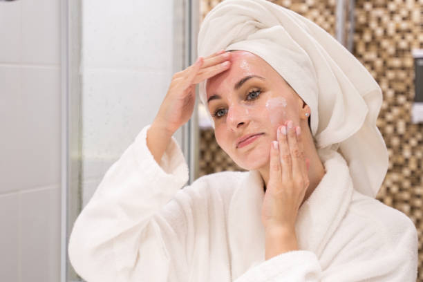 mujer se encarga de la cara aplicando gel limpiador en el baño - facial cleanser fotografías e imágenes de stock