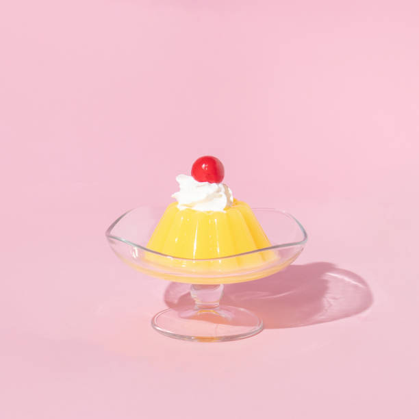 gelatina amarela no prato com cereja em cima no fundo rosa pastel. ideia de sobremesa estética estilo retrô dos anos 70 ou 80. conceito mínimo de comida. - food still life sweet food pudding - fotografias e filmes do acervo