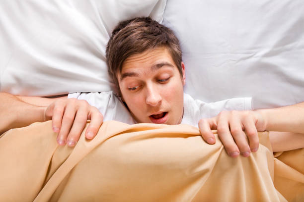 Worried Man in the Bed Worried Man look under the Blanket in the Bed at the Home erection stock pictures, royalty-free photos & images