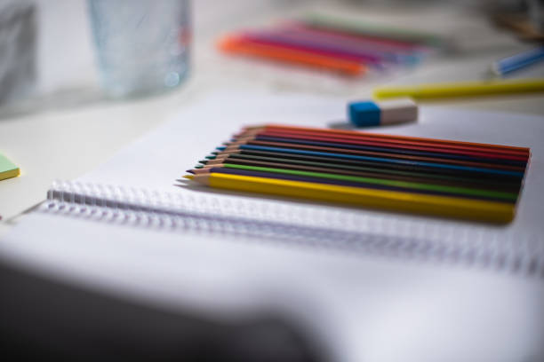 Crayons, colored pencils on the table in the notebook. Closeup of brand new colored pencils