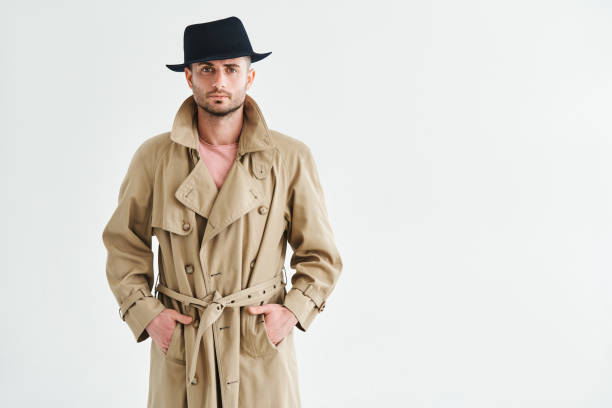 istock Young man in a trench coat and hat over white background with copy space 1422232616