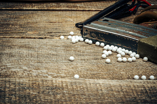 Close up photo of airsoft gun magazine and airsoft balls on wooden background