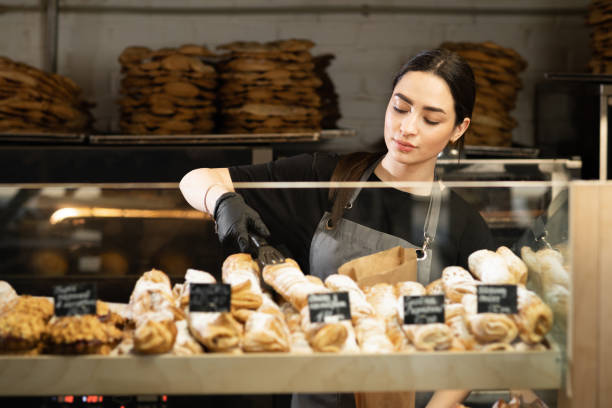 kelnerka kawiarnia dziewczyna kładzie świeże wypieki na gablocie kawiarni, pracownik piekarni - bread food basket sweet bun zdjęcia i obrazy z banku zdjęć