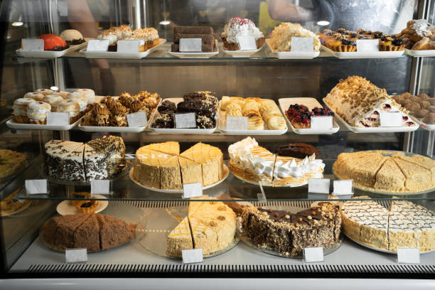 Pastry shop glass display with selection of cream or fruit cake, bakery shop with various flavors of cake Pastry shop glass display with selection of cream or fruit cake, bakery shop with various flavors of cake with price dessert pie stock pictures, royalty-free photos & images