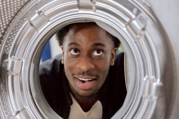 View from inside the drum, a man has bought a new washing machine, looks at it with curiosity inside, smiles, is interested shocked fascinated.