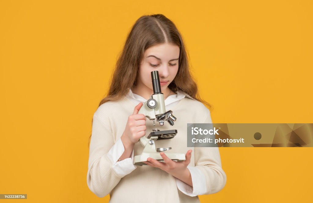 serious child with microscope on yellow background serious child with microscope on yellow background. Science Stock Photo