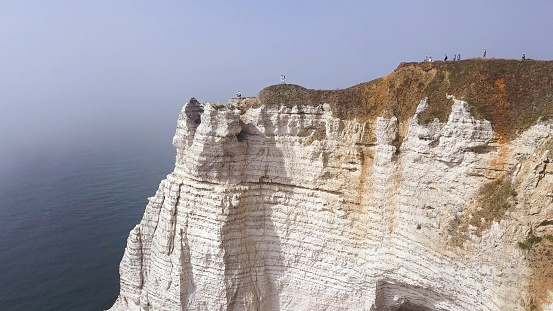 Couple traveling together on white cliff edge on blue sky background, lifestyle concept. Young couple of travelers on a hill with stunning views of the ocean.