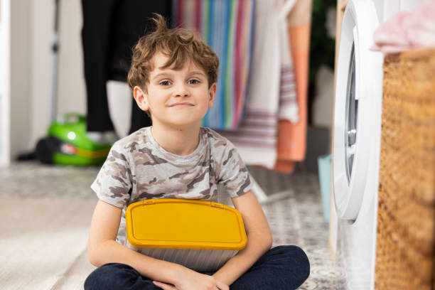 istock A little boy is sitting on the bathroom floor next to an open washing machine holding a box of laundry capsules in his hands, learning to use the equipment, using detergent 1422242589