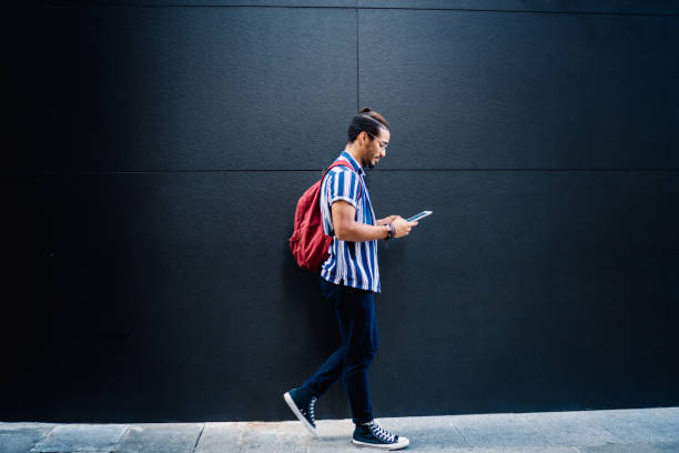 hombre fresco concentrado usando tableta caminando por la calle - hipster people surfing the net internet fotografías e imágenes de stock