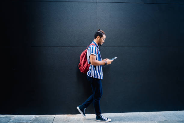 concentrated cool man using tablet walking on street - hipster people surfing the net internet imagens e fotografias de stock