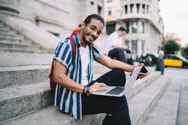 istock Cheerful young man using laptop on stairs 1422242676