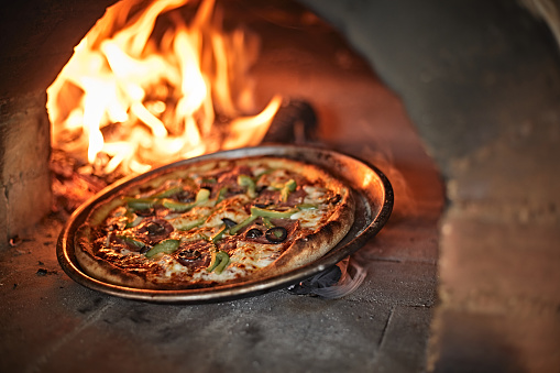 Fresh pizza in the oven with fire and wood